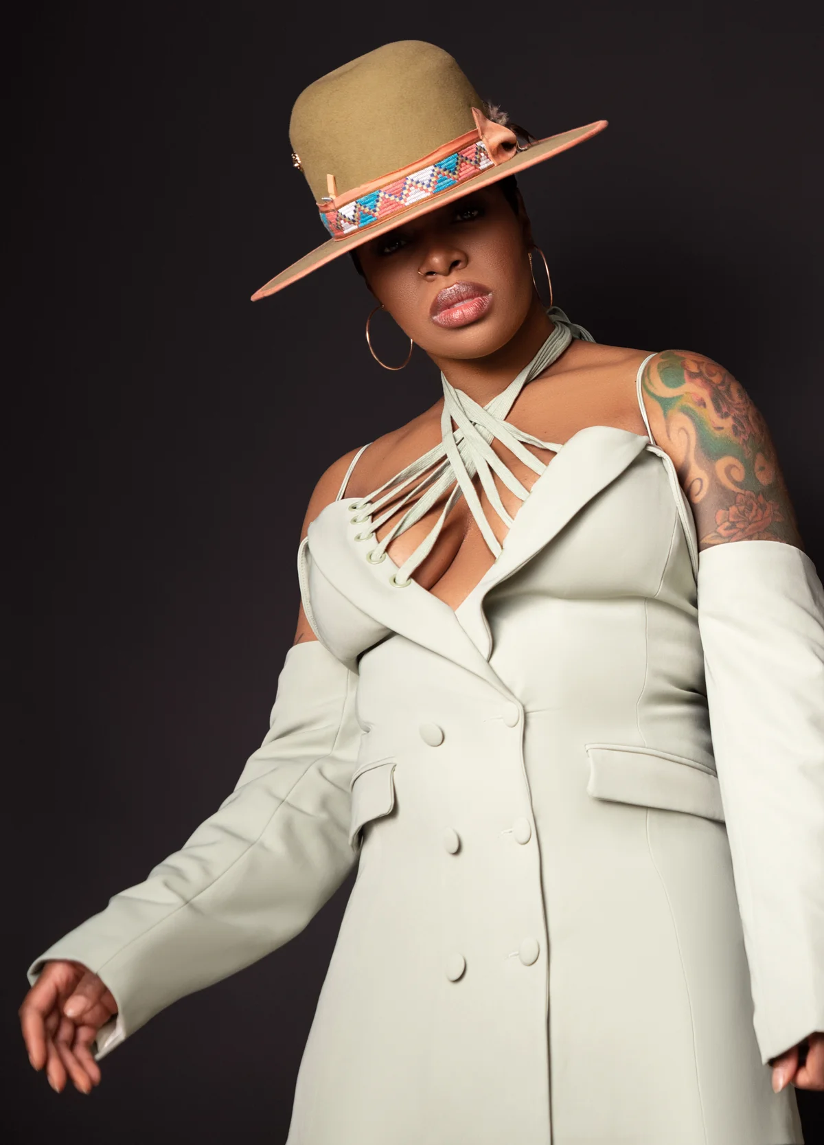 Ta'Rhonda Jones in a sage suit and wide-brim hat against black